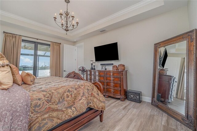 bedroom featuring crown molding, a tray ceiling, a chandelier, and light wood-type flooring