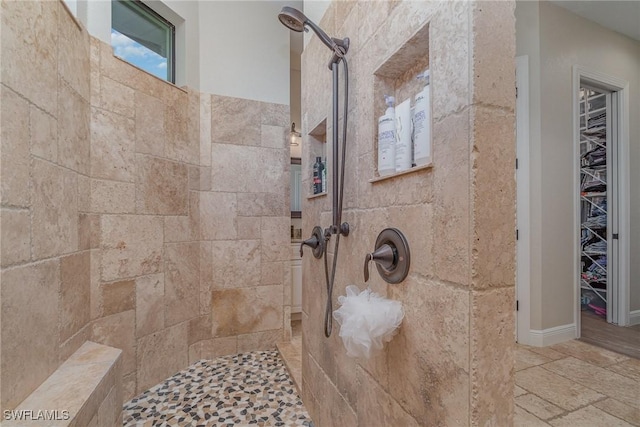 full bath with a tile shower and stone tile floors