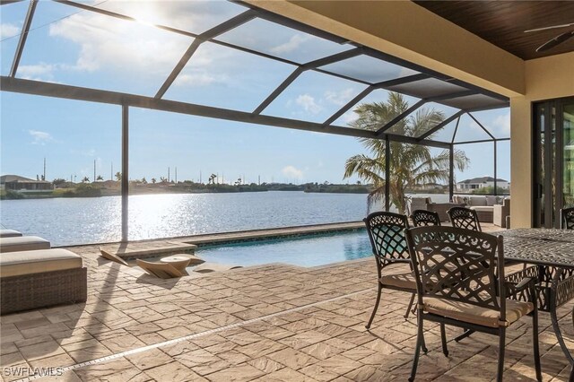 view of patio / terrace with glass enclosure, a ceiling fan, an outdoor pool, and a water view