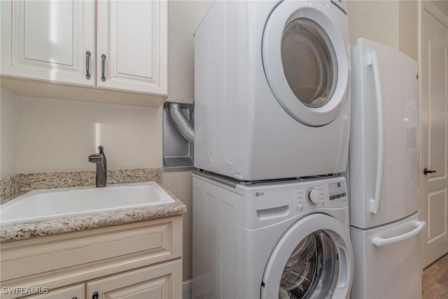 laundry area with sink, cabinets, and stacked washer and clothes dryer