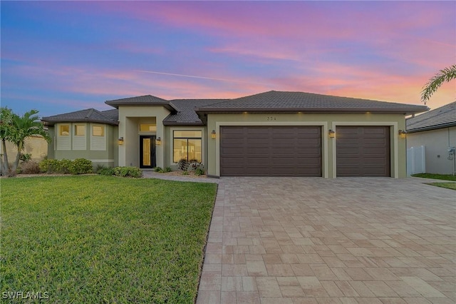 prairie-style home featuring a garage and a yard