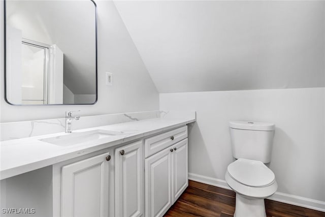 bathroom with baseboards, toilet, wood finished floors, vaulted ceiling, and vanity