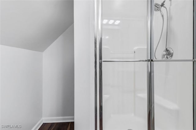 full bathroom featuring a shower stall, baseboards, and wood finished floors