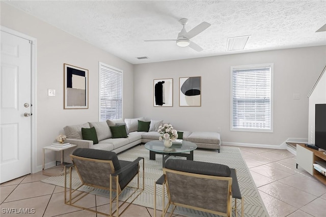 living room featuring light tile patterned floors, a textured ceiling, visible vents, and a ceiling fan