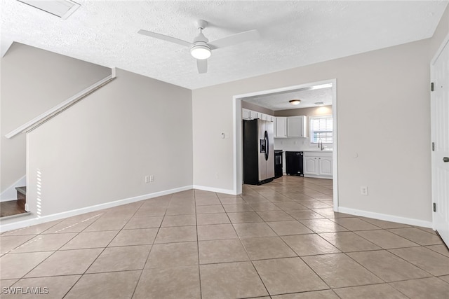 unfurnished room with light tile patterned floors, stairway, a ceiling fan, a textured ceiling, and baseboards