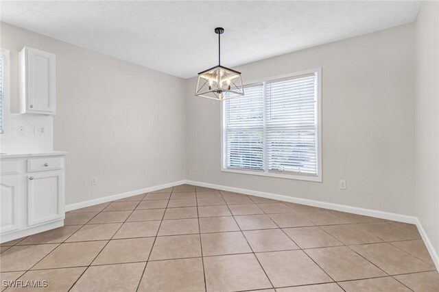 unfurnished dining area with a chandelier and baseboards