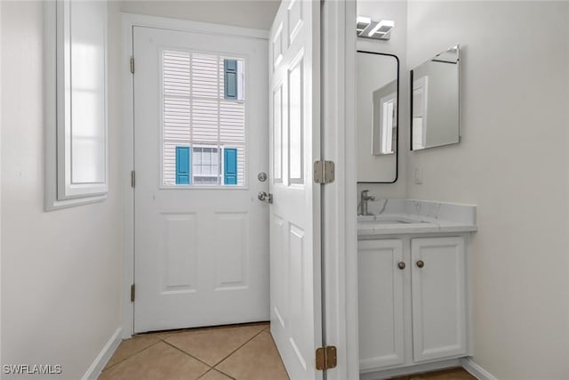 entryway featuring light tile patterned floors, baseboards, and a sink