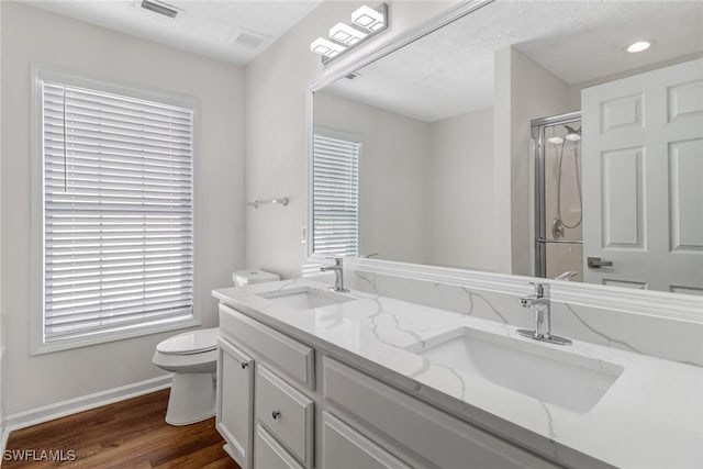 bathroom featuring wood finished floors, a stall shower, a sink, and toilet