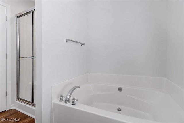 full bathroom featuring a garden tub, a shower stall, and wood finished floors