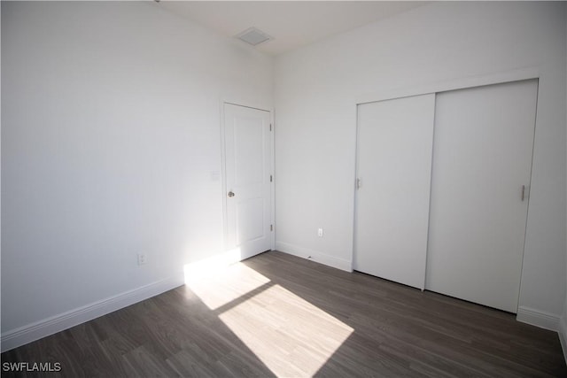 unfurnished bedroom featuring dark hardwood / wood-style flooring and a closet