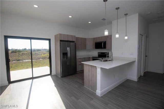 kitchen featuring kitchen peninsula, a breakfast bar area, appliances with stainless steel finishes, decorative light fixtures, and sink