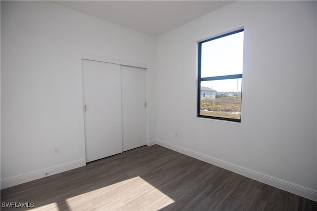 unfurnished bedroom with a closet and dark hardwood / wood-style flooring