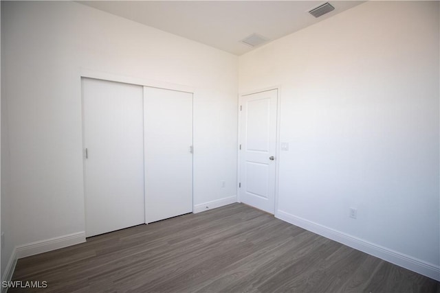 unfurnished bedroom featuring a closet and dark hardwood / wood-style flooring