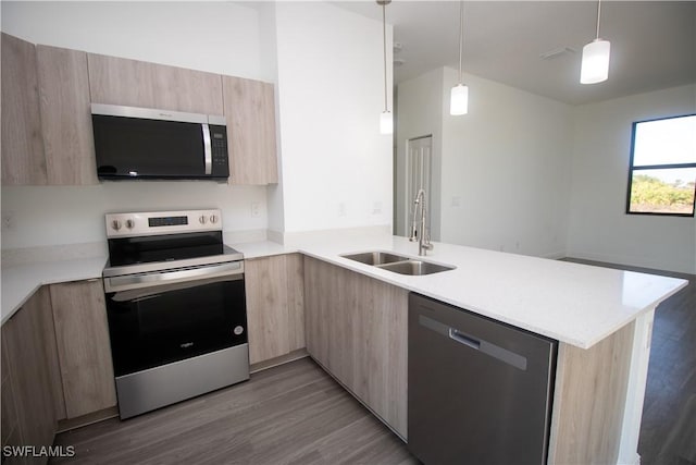 kitchen with kitchen peninsula, stainless steel appliances, light brown cabinets, pendant lighting, and sink