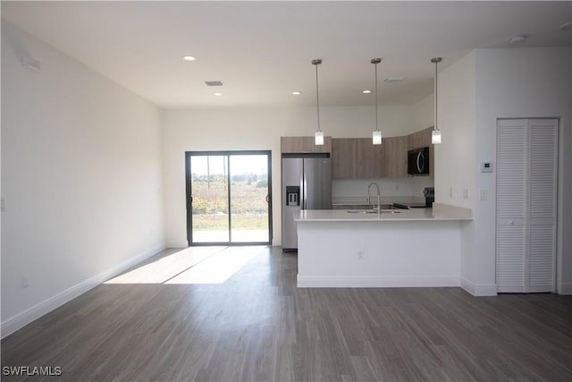 kitchen with stainless steel refrigerator with ice dispenser, dark hardwood / wood-style floors, stove, hanging light fixtures, and sink