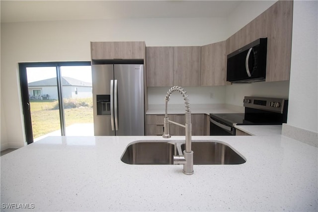 kitchen with sink, light stone counters, and stainless steel appliances