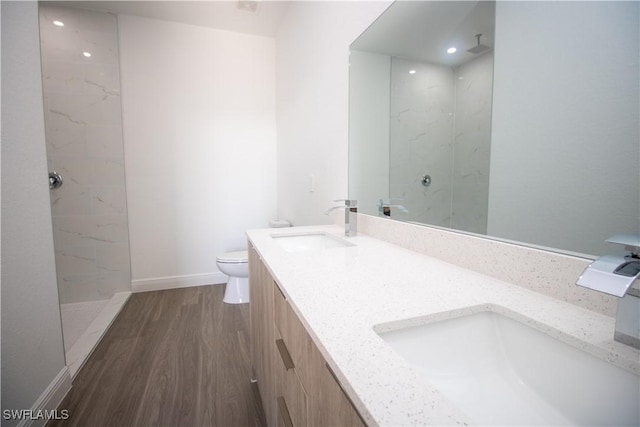 bathroom with toilet, vanity, wood-type flooring, and a shower