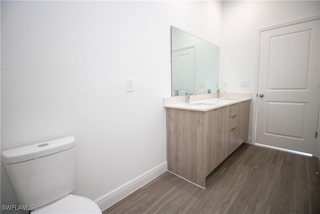 bathroom with toilet, vanity, and hardwood / wood-style floors