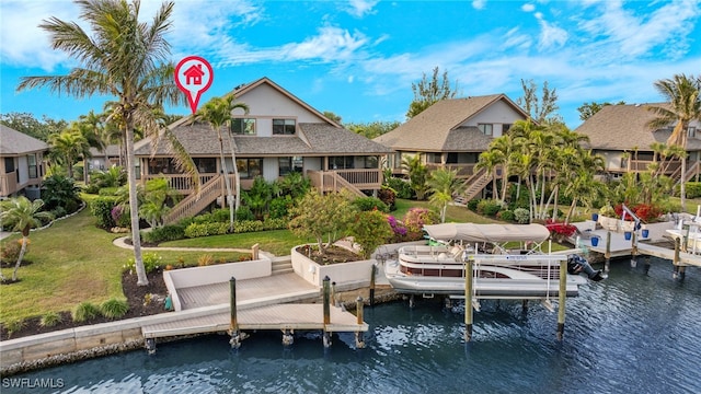 back of house featuring a water view and a lawn