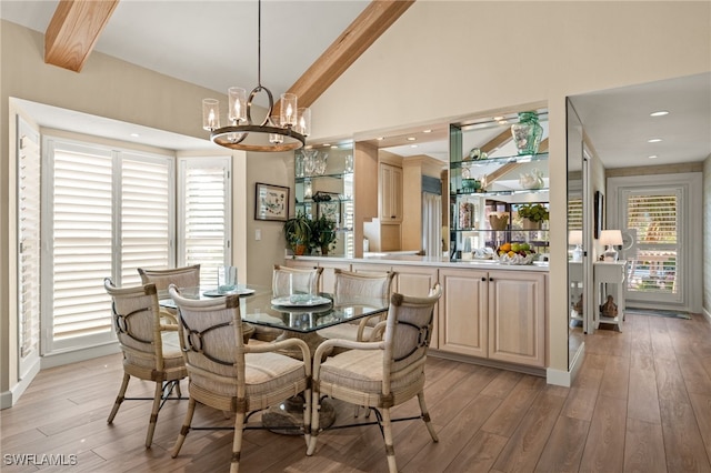 dining space featuring beam ceiling, high vaulted ceiling, an inviting chandelier, and light hardwood / wood-style flooring