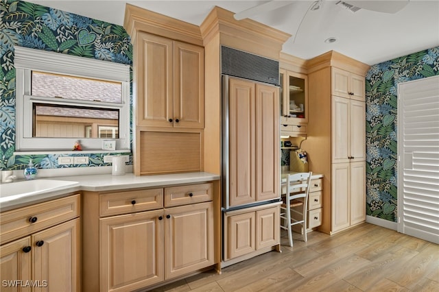 kitchen with ceiling fan, light brown cabinets, light wood-type flooring, paneled built in refrigerator, and sink