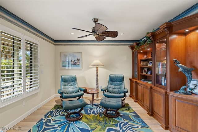 living area featuring ceiling fan, light wood-type flooring, and crown molding