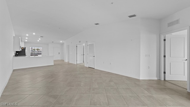 unfurnished living room featuring light tile patterned floors and vaulted ceiling