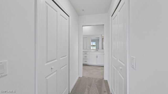 hallway featuring light carpet and sink