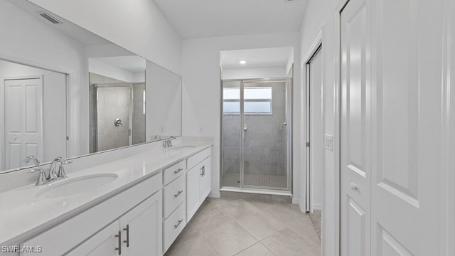 bathroom featuring tile patterned flooring, a shower with shower door, and vanity