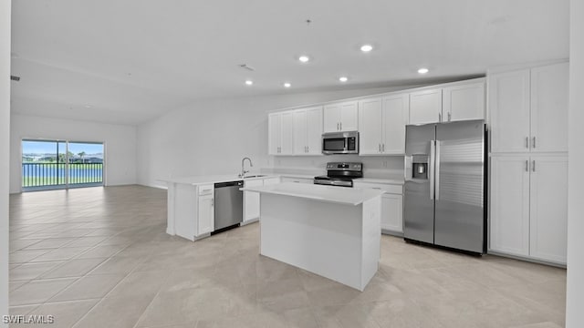 kitchen with vaulted ceiling, kitchen peninsula, sink, white cabinetry, and appliances with stainless steel finishes