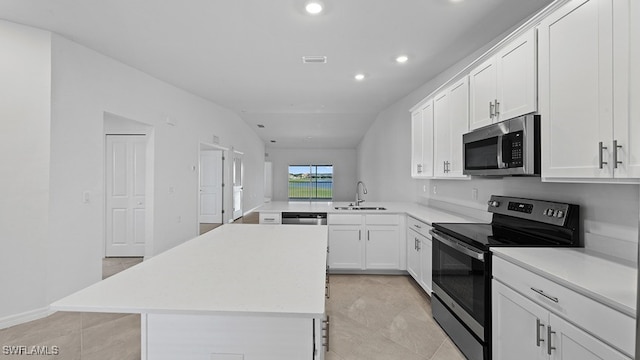 kitchen featuring white cabinetry, appliances with stainless steel finishes, lofted ceiling, a kitchen island, and sink