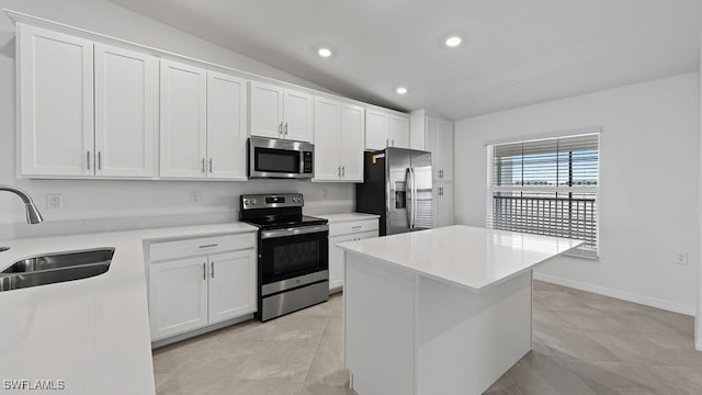 kitchen with appliances with stainless steel finishes, white cabinetry, a kitchen island, and sink