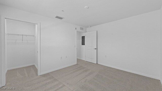 unfurnished bedroom with light colored carpet, electric panel, and a closet