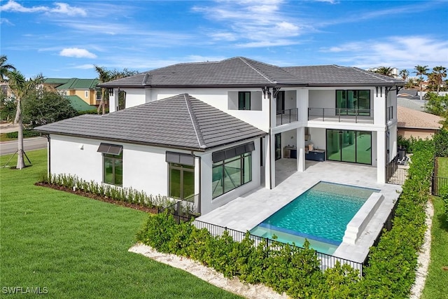 rear view of property with a balcony, a fenced in pool, a patio area, and a lawn