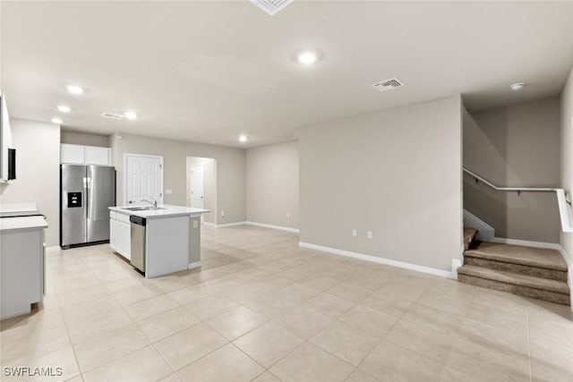 kitchen featuring white cabinetry, a center island with sink, appliances with stainless steel finishes, light tile patterned flooring, and sink