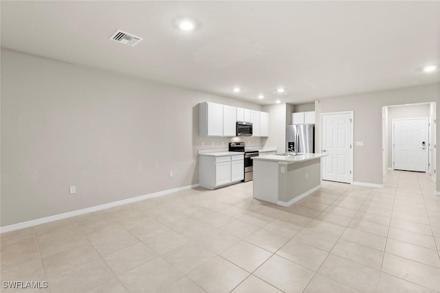 kitchen featuring light tile patterned floors, stainless steel appliances, white cabinetry, and an island with sink