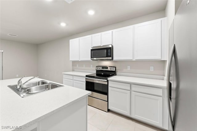 kitchen featuring sink, white cabinetry, light tile patterned floors, and stainless steel appliances