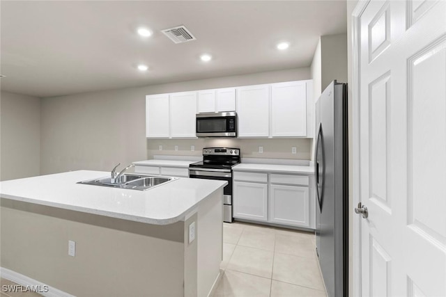 kitchen with appliances with stainless steel finishes, white cabinetry, sink, light tile patterned floors, and a center island with sink