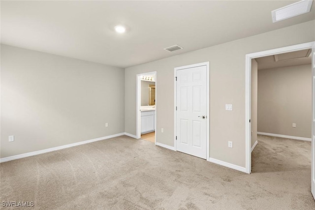 unfurnished bedroom featuring light colored carpet and ensuite bath