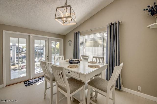 dining space featuring lofted ceiling, a chandelier, french doors, and a textured ceiling