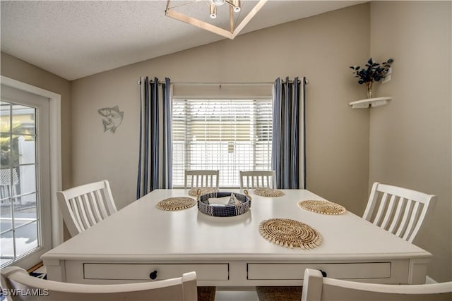 dining area with vaulted ceiling and a textured ceiling