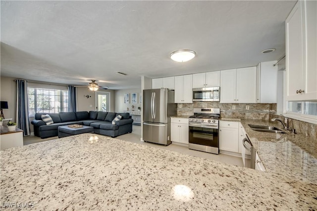 kitchen featuring sink, white cabinetry, light stone counters, tasteful backsplash, and appliances with stainless steel finishes