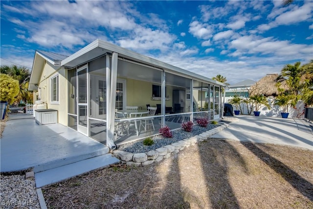 view of side of property featuring a patio area and a sunroom