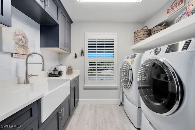 laundry area featuring light hardwood / wood-style floors, cabinets, sink, and washing machine and dryer