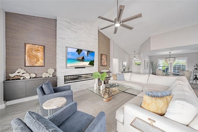 living room with ceiling fan, light hardwood / wood-style floors, a fireplace, and high vaulted ceiling