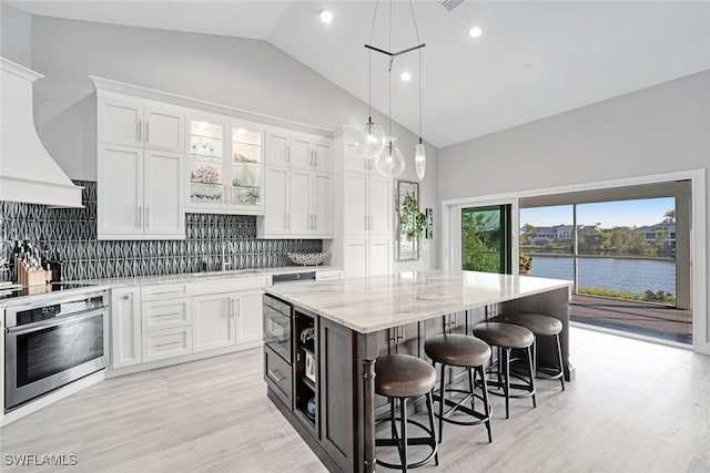 kitchen with a kitchen island, white cabinets, and oven