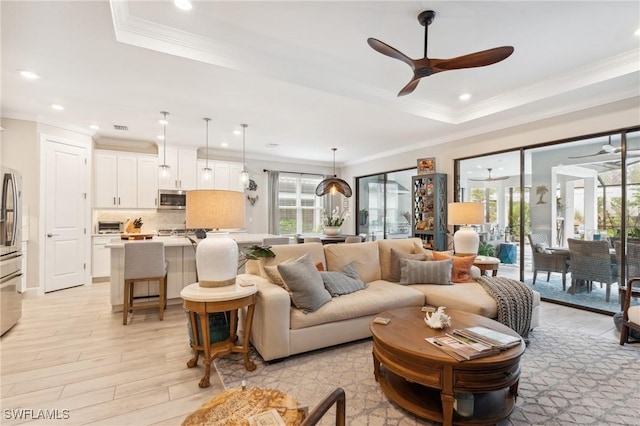 living room with ceiling fan, crown molding, light hardwood / wood-style flooring, and a raised ceiling