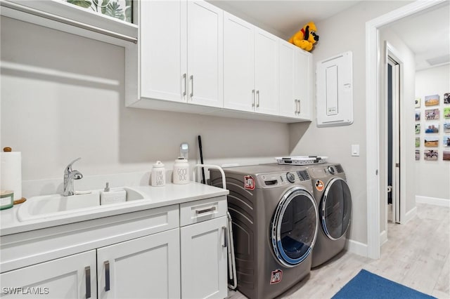 washroom with electric panel, light hardwood / wood-style floors, sink, separate washer and dryer, and cabinets