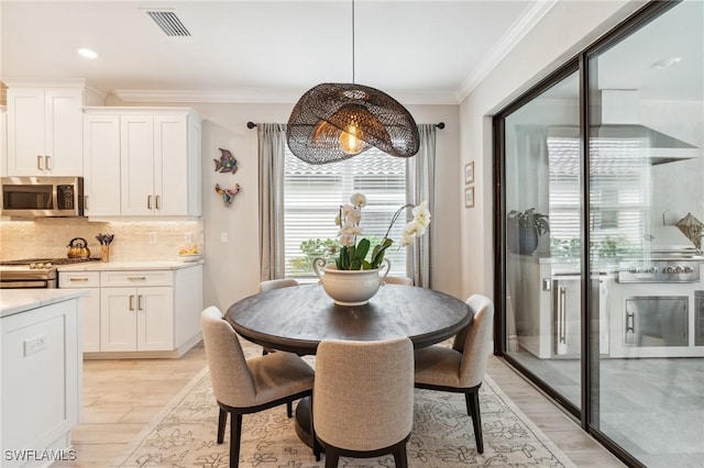 dining room featuring ornamental molding and light hardwood / wood-style flooring