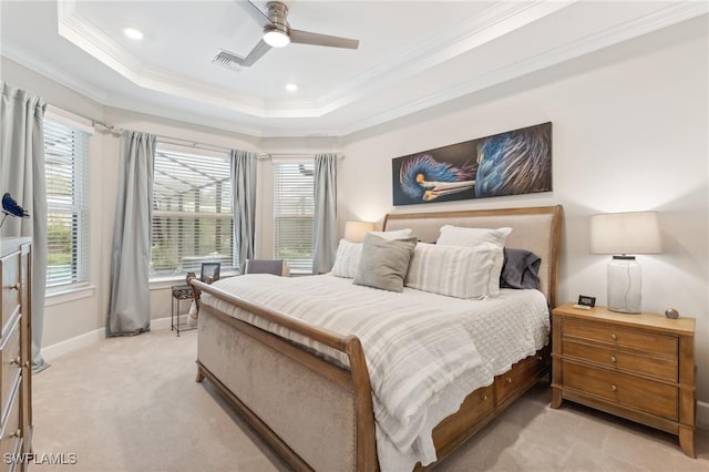 bedroom featuring light carpet, ceiling fan, crown molding, and a tray ceiling